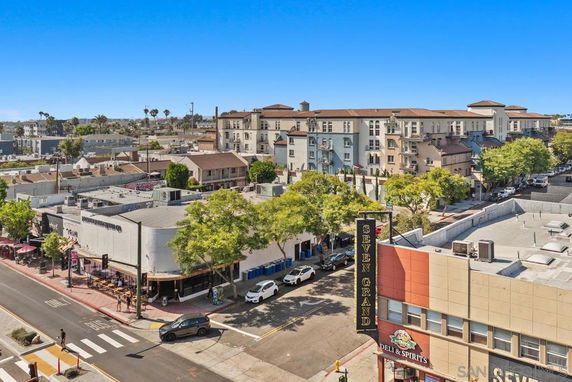 View of an urban area with mixed-use buildings and a street with parked cars.