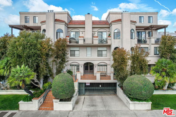 Front view of a multi-story residential building with a gated entrance and balconies.