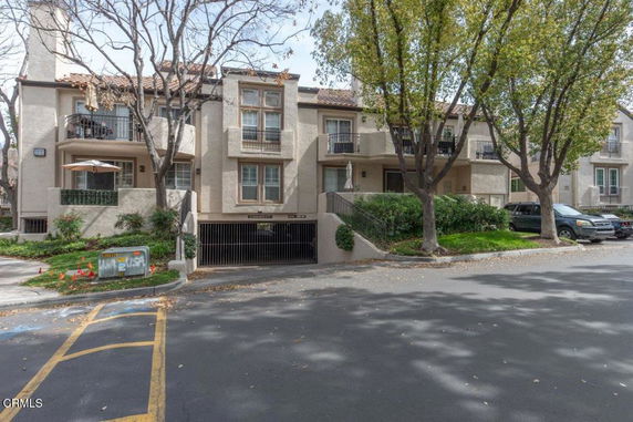 Front view of a two-story apartment building with multiple balconies and a parking entrance.