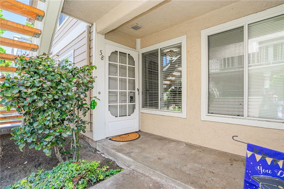 Front view of an entrance to a house with a glass-paneled door and large windows.