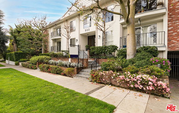 Front view of a multi-story residential building with balconies and landscaped gardens.