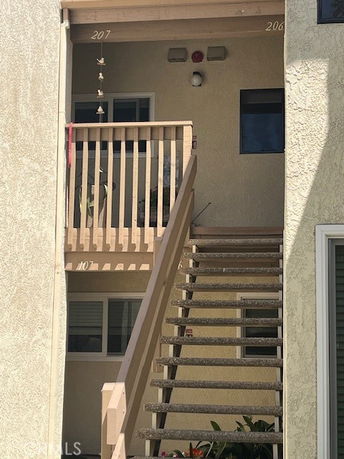 Front view of a building entrance with outdoor stairs leading to upper-level apartments.