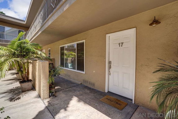 Exterior view of an apartment building with an entryway marked with door number 17 and potted plants.