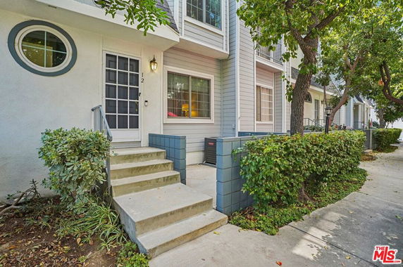 Front view of a townhouse with white and light gray siding and a small staircase leading to the entrance.