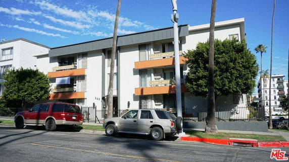 Front view of a multi-story building with balconies and a flat roof.