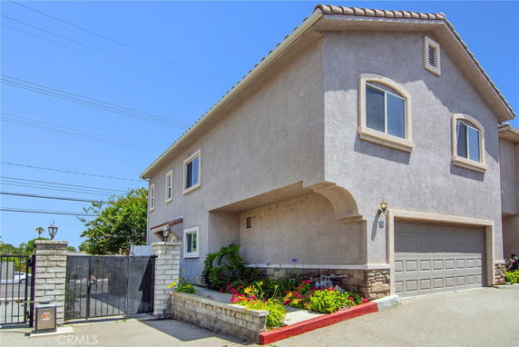 Front view of a two-story house with a gated entrance and garage.