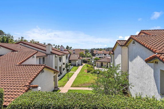View of multiple residential buildings with red-tiled roofs and walkways in a housing complex.