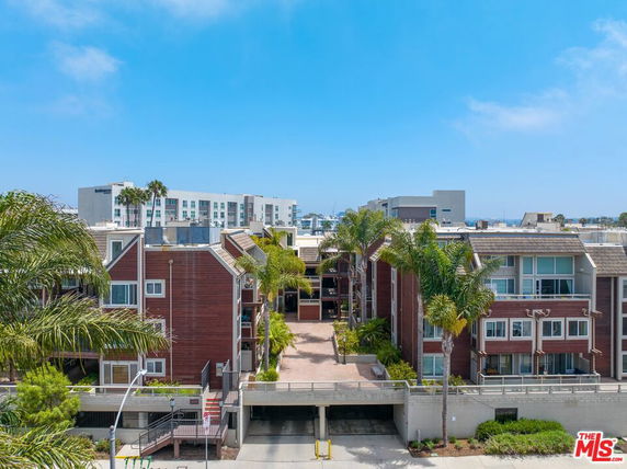 View of residential complex with multiple buildings and palm trees.