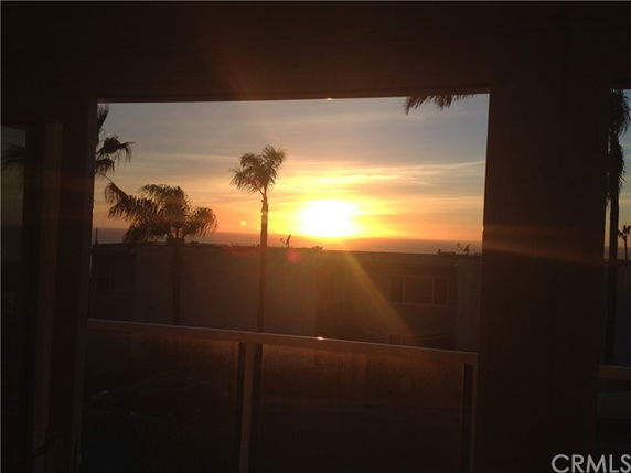 Sunset view through a window with palm trees in the distance.