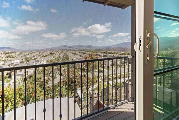 View from a balcony looking out over a neighborhood and distant mountains.
