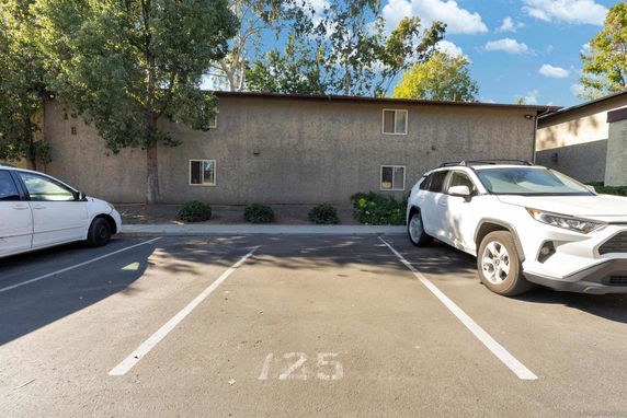 Outdoor parking area with marked parking spots and two parked vehicles, one white and one partially visible.