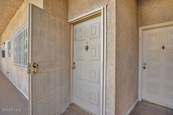 Front view of a building entrance showing a secure screen door and main door.