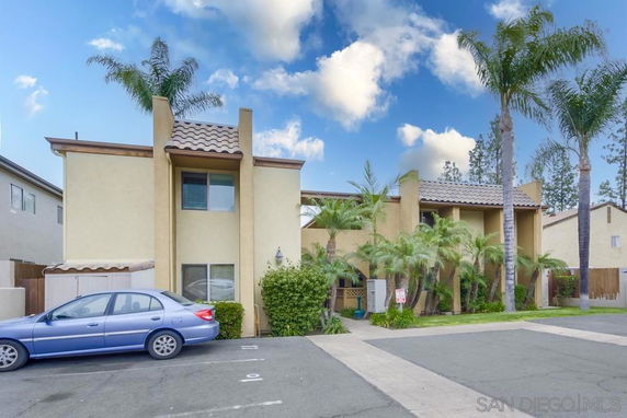 Front view of a two-story building with palm trees and a tiled roof.