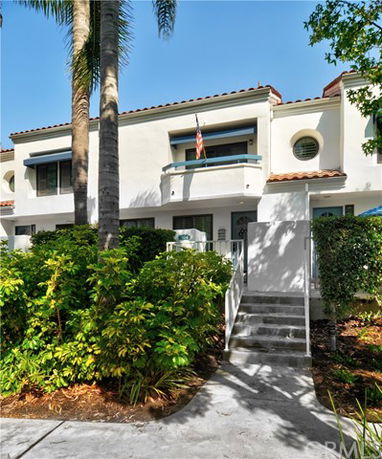 Front view of a multi-story house with a small balcony and steps leading to the entrance.