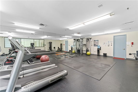 Indoor gym area with exercise equipment and mirrors on the walls.