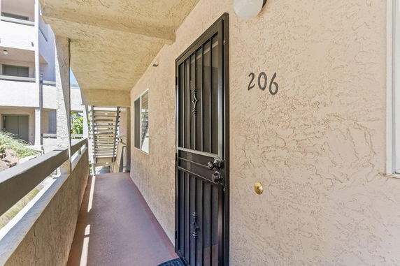 Exterior corridor view leading to a unit door numbered 206 in a multi-story building.