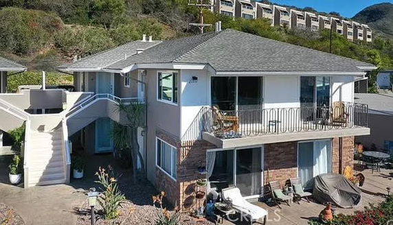 Front view of a two-story house with a staircase and balcony.