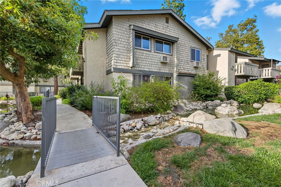 Front view of a multi-story building with a small bridge and landscaped garden.