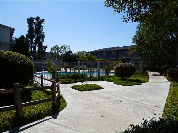 Outdoor swimming pool surrounded by a fence and greenery.