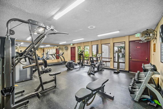 Indoor gym area with exercise equipment and weights.