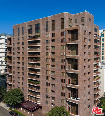 Front view of a multi-story brick apartment building with balconies.