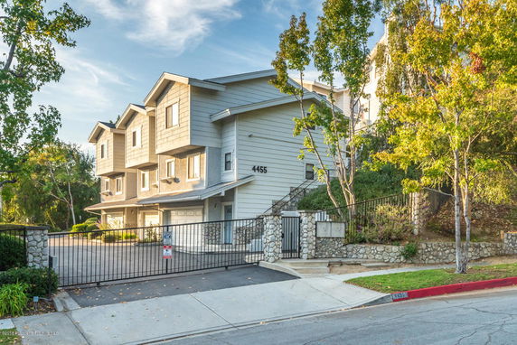 Front view of a multi-story house with garages and a gated entrance.