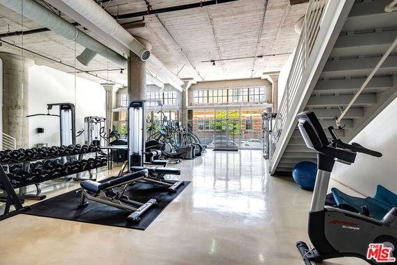 Interior of a gym with exercise equipment and large windows.
