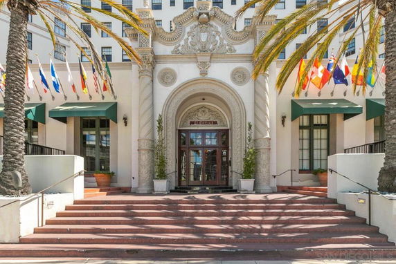 Front view of a building with decorative entrance and multiple flags above the doorway.