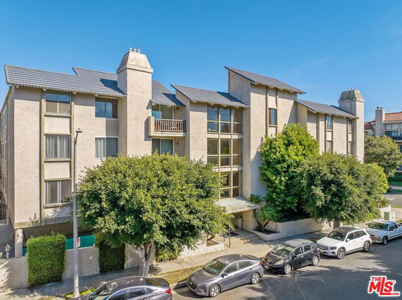 Front view of a multi-story residential building with balconies and large windows.