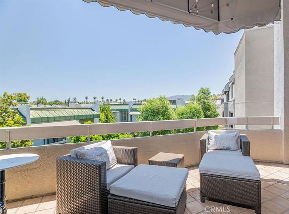 Outdoor seating area with views of nearby buildings and trees.