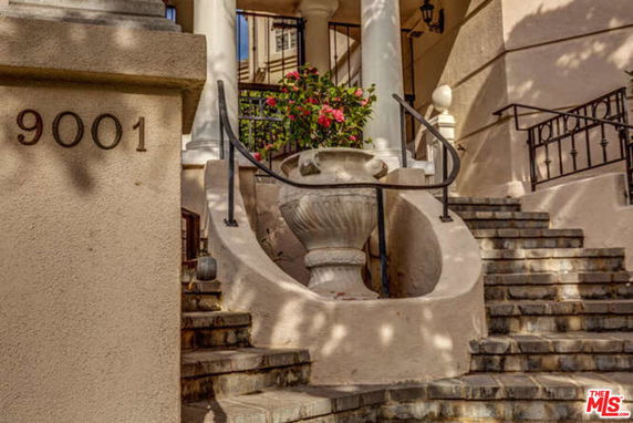 Front view of a building entrance with stairs and a large planter.