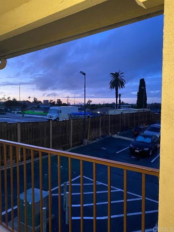 View from a building showing a parking area and surrounding landscape with palm trees and vehicles.