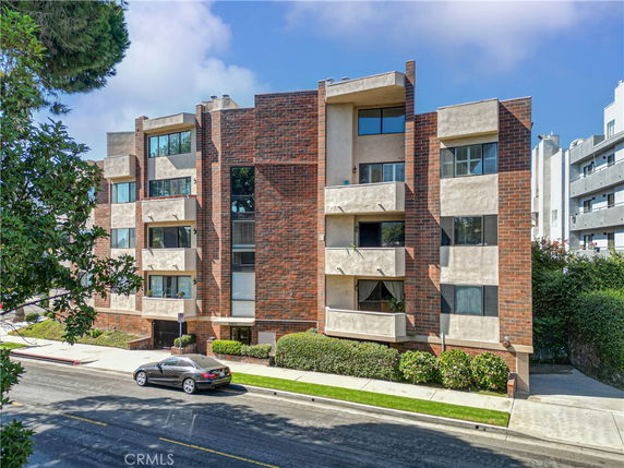 Front view of a multi-story apartment building with brick and stucco facade.