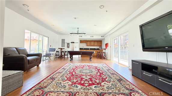 Interior of a clubhouse with seating area, pool table, TV, and open kitchen.