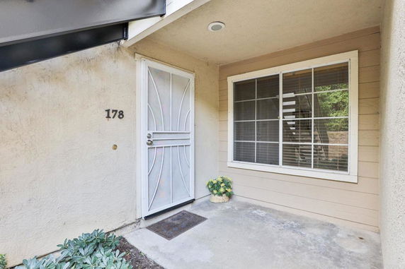 Front view of a house entrance with a metal security door and window with blinds.