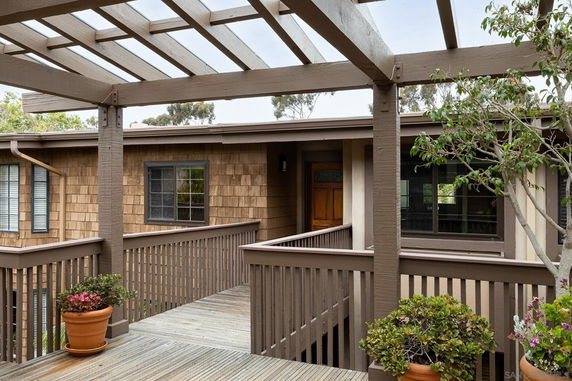 Front view of a house with wooden siding and a pergola-covered entrance.