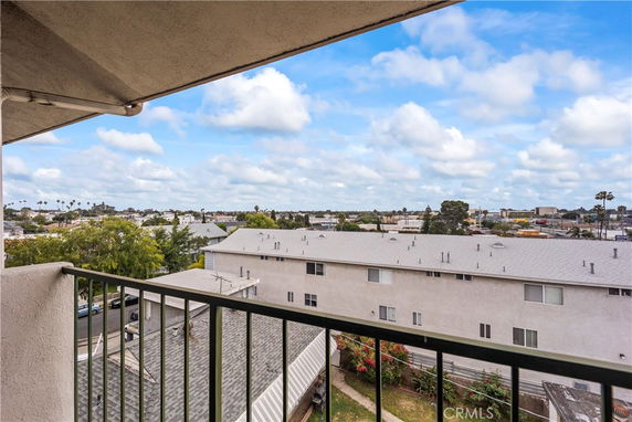Panoramic view from a balcony overlooking buildings and a distant cityscape.