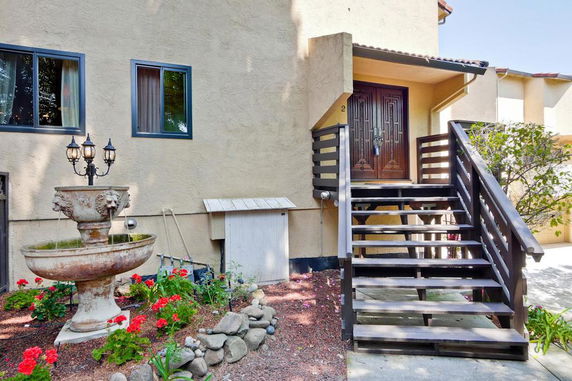 Front view of a house with wooden staircase and decorative fountain.
