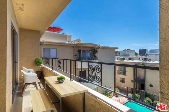 Balcony view overlooking a swimming pool and adjacent buildings.