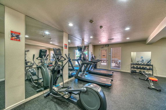 Indoor gym area with exercise equipment including treadmills and elliptical machines.