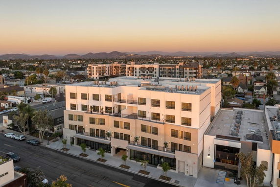Front view of a modern multi-story apartment building with large windows and balconies.