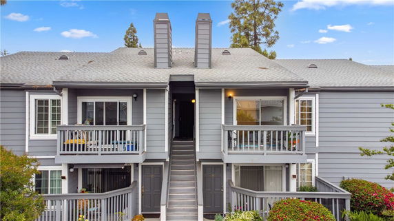Front view of a two-story townhouse with balconies and a central staircase.
