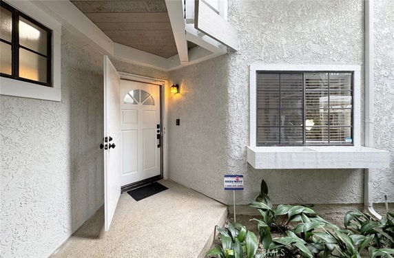 Front view of a house entrance with an open white door and adjacent window.