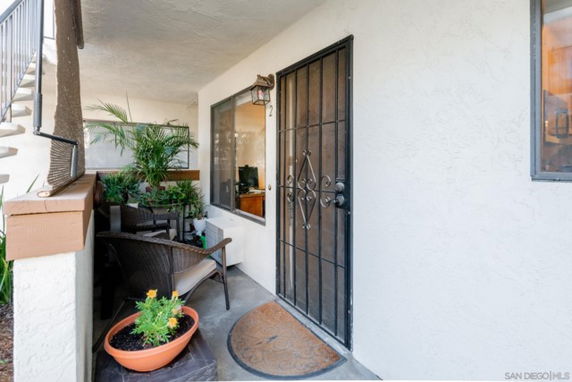 Front view of a house with a metal security door and small outdoor seating area.
