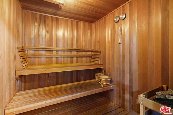 Wood-paneled sauna room with benches and a bucket.