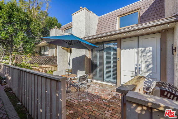 Front view of a house with large doors and a patio area with an umbrella and seating.