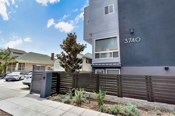 Front view of a modern multi-story building with a fence and address displayed as 3740.
