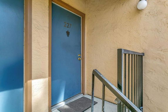 Front view of a building entrance with a blue door numbered 227 and a railing.