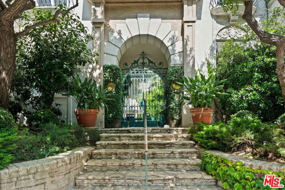 Front view of a house with an ornate gate and stone steps leading to the entrance.