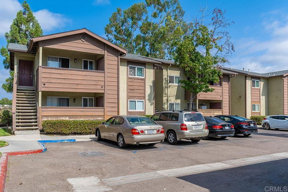 Front view of a multi-story apartment building with a parking area in front.